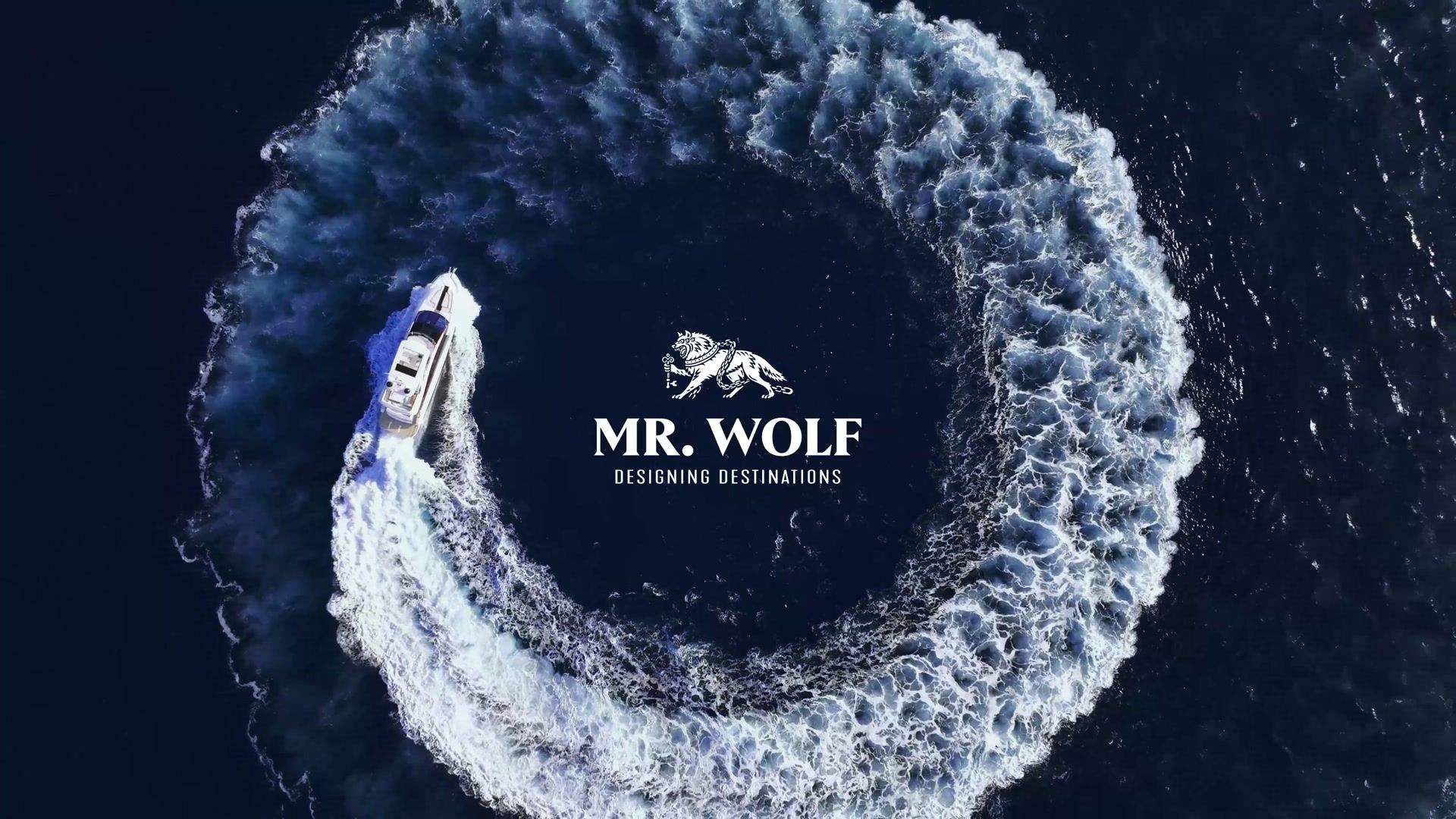 Aerial view of a yacht carving a full white circle in deep blue ocean